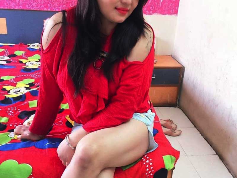 beautiful chinky girl in red top and shorts sitting on bed in a room