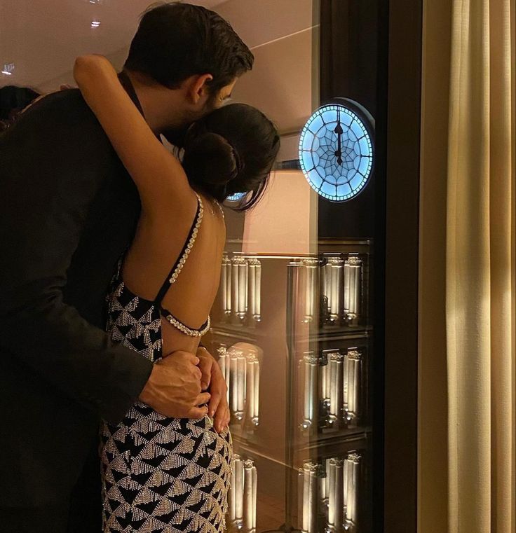 a girl in a backless dress hugging a guy