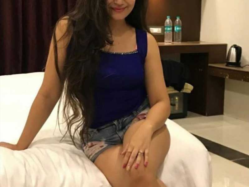 hot girl in royal blue top and jeans shorts sitting on bed in hotel room